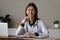 Head shot portrait smiling female therapist doctor sitting at desk