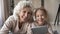 Head shot portrait smiling mature woman with granddaughter using tablet