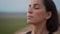 Head shot portrait of young peaceful woman breathing fresh air, enjoying deep meditation with closed eyes