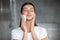 Head shot satisfied woman cleaning skin with facial cleansing sponge