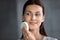 Head shot smiling woman cleaning skin with facial cleansing sponge