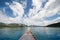 Head of wooden boat cruising in the lake with mountains view and cloudy blue sky background