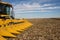 Head of Yellow Combine in Harvested Field