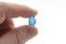 Headache pain relief, pharmaceutical treatment and sickness fighting concept with close up fingers holding blue gel capsule