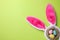 Headband with Easter bunny ears and dyed eggs in nest on green background, flat lay. Space for text