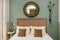 Headboard of a bedroom with contemporary decoration with upholstered headboard, round mirror with metal frame, wall lamp and