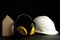 Headphone Safety with white hardhat on black background. Home builder safety tools