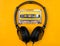 Headphones and audio cassette on yellow