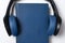 Headphones and blue book. Audiobook concept. White copy space background closeup