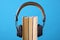 Headphones and books but against blue background, concept of audio books, listening to a book