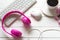 Headphones and coffee cup on wooden desk table with pink flower. Music and lifestyle concept.