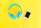 Headphones connected to white smartphone on yellow background