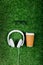 Headphones, eyeglasses and coffee to go on green lawn
