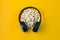 Headphones and lots of popcorn on a yellow background