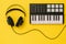 Headphones and music mixer on bright yellow background. The concept of workplace organization.