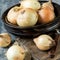 Heads of fresh golden onions in a round wooden bowl .