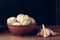 Heads of garlic in a clay bowl and cloves on a wooden table