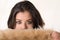 Headshot attractive brunette facing camera covering half her face with brown fur clothing, white studio background