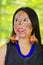 Headshot beautiful amazonian exotic woman with facial paint and black dress, posing happilyfor camera, forest background