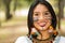 Headshot beautiful Amazonian woman, indigenous facial paint and earrings with colorful feathers, posing happily for