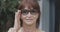 Headshot of beautiful confident senior woman in eyeglasses looking at camera and smiling. Close-up portrait of redhead