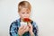 Headshot of beautiful little boy licking big lollipop in one hand and smartphone in other. A liitle male child messaging with his