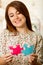 Headshot charming brunette woman holding up big puzzle pieces in pink and blue, smiling happily to camera, white studio