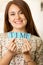 Headshot charming brunette woman holding up small letters spelling the word time and smiling to camera