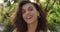 Headshot of cheerful brunette woman with wavy hair laughing while looking to camera. Close up view of attractive latino