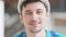 Headshot of cheerful young confident builder putting on hard hat smiling looking at camera. Close-up portrait of