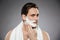 Headshot of concentrated handsome man putting shaving foam on fa