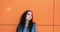 Headshot of confident pretty young woman, on orange wall background . Blank And Positive human emotion facial expression