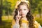 Headshot cute little girl wearing beautiful yellow dress with matching head band, posing for camera, green forest