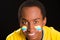 Headshot dark skinned male wearing yellow football shirt in front of black background, flag facial paint, facing camera