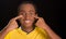 Headshot dark skinned male wearing yellow football shirt in front of black background, using fingers applying facepaint