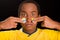 Headshot dark skinned male wearing yellow football shirt in front of black background, using fingers applying facepaint