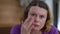 Headshot front view of thoughtful worried Caucasian woman looking at camera touching wrinkles on face skin. Close-up