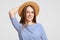 Headshot of good looking brunette girl in fashionable summer hat, has pleasant smile, dressed in stylish outfit, ready to have dat