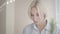 Headshot of gorgeous blond Caucasian woman drinking tea or coffee indoors and smiling. Close-up portrait of charming