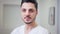 Headshot of handsome young Middle Eastern doctor with brown eyes looking at camera smiling. Close-up portrait of