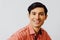 Headshot hispanic latino man black hair smiling handsome young adult wearing melon shirt over gray background looking at