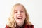 Headshot of a laughing young blonde preteen girl on a white studio background