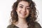 Headshot lucky dreamy cute armenian woman curly hairstyle smiling hopefully upbeat positive mood enjoying nice friendly