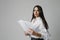 Headshot of middle-aged woman, mentor coach stays over white wall holds papers.