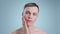 Headshot of millennial man touching his face while looking to camera . Portrait of male handsome model with naked