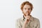 Headshot of mysterious handsome and self-assured redhead mature male with beard and stylish hairstyle saying shh while