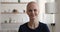 Headshot portrait bald woman sitting indoor smiling look at camera