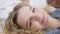 Headshot portrait of cheerful slim gorgeous Caucasian blond woman looking at camera lying in cozy bed at home. Close-up