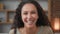 Headshot portrait closeup indoors happy female face cheerful Hispanic woman with curly hair feels good mood happy laughs