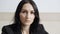 Headshot portrait of confident serious Caucasian woman with black hair and brown eyes looking at camera. Close-up of